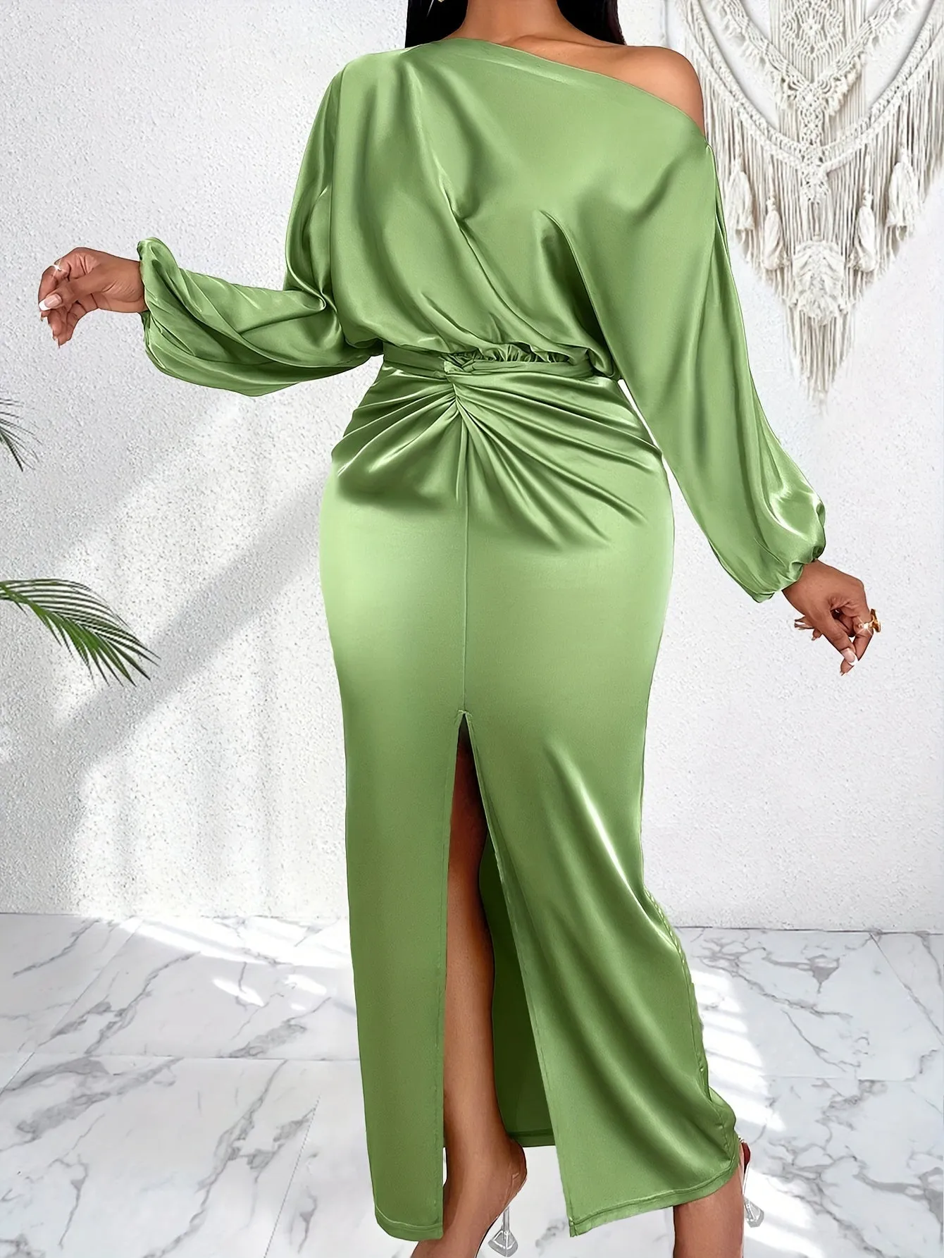 An elegant women's long-sleeve satin dress featuring a twist detail, an asymmetrical shoulder, and a high slit in a solid color.